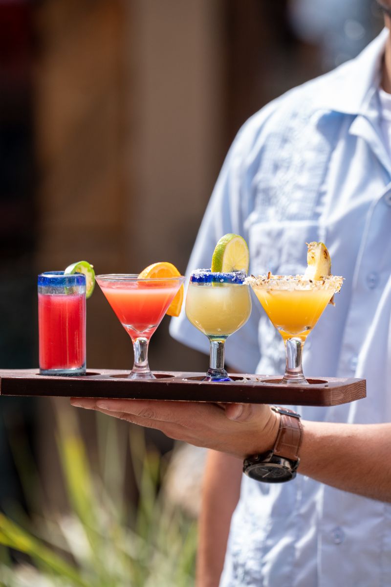 Server carrying a flight of four margaritas at La Posta de Mesilla